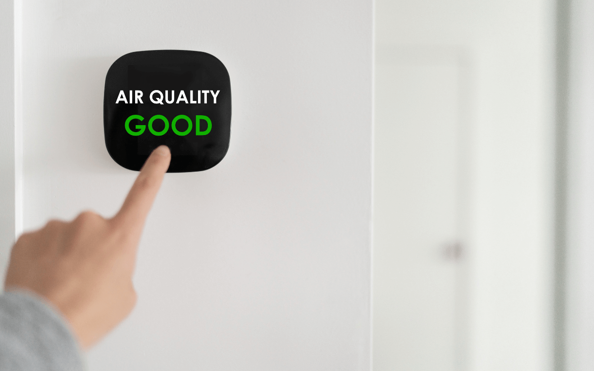 IAQ consultants in Singapore demonstrating air quality monitor showing good indoor air quality reading.